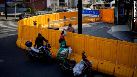 Un repartidor pasa comida a una mujer por encima de las barreras de un área cerrada en Shanghái el 23 de marzo de 2022. 