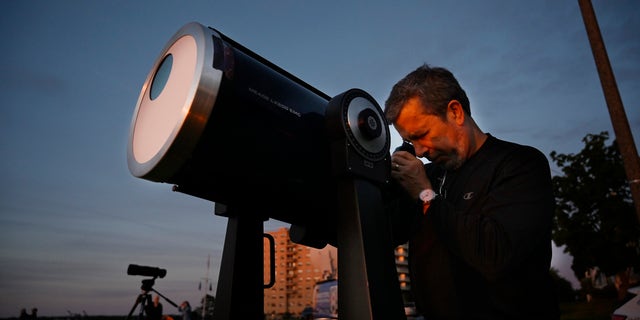 Robert Burgess, astrónomo jefe del sur de Maine, instala un telescopio con filtros solares para observar un eclipse parcial desde East Party en Portland el jueves 10 de junio de 2021.