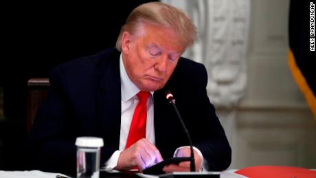 El expresidente Donald Trump mira su teléfono durante una mesa redonda con gobernadores estatales sobre la reapertura de pequeñas empresas en Estados Unidos, en el comedor de la Casa Blanca en Washington, el 18 de junio de 2020. 