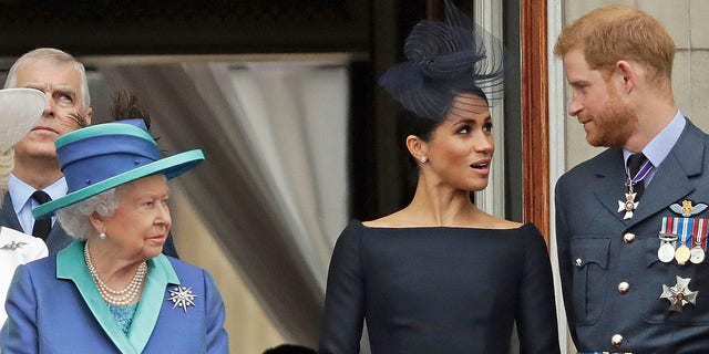 La reina Isabel, Meghan Markle y el príncipe Harry se paran en un balcón para ver un vuelo de la RAF sobre el Palacio de Buckingham en 2018.