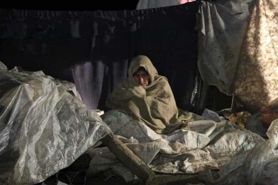 Una mujer en el estado de Paktika que se quedó sin hogar por el terremoto intenta calentarse.
