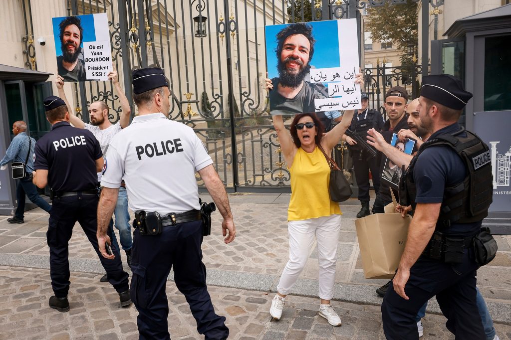 La familia y los amigos del estudiante se pararon en una acera en París y agitaron carteles que pedían 