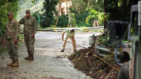 La Guardia Nacional fuerza el tráfico directo mientras el residente Luis Nogueira ayuda a despejar una carretera dañada por el huracán Fiona en Cayai, Puerto Rico, el martes.