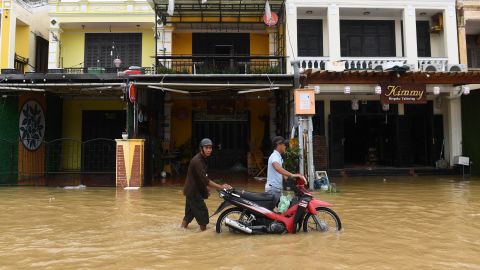 La gente empuja una motocicleta en una calle inundada en la ciudad de Hoi An, provincia de Quang Nam, el 28 de septiembre de 2023.