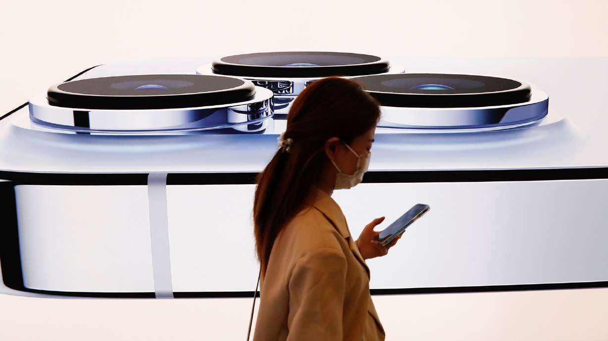 A woman walks past an image of an iPhone 13 Pro on the day the new Apple iPhone 13 series went on sale, in Beijing, China, in September 2021. Apple is expected to debut its iPhone 14 lineup on Wednesday.