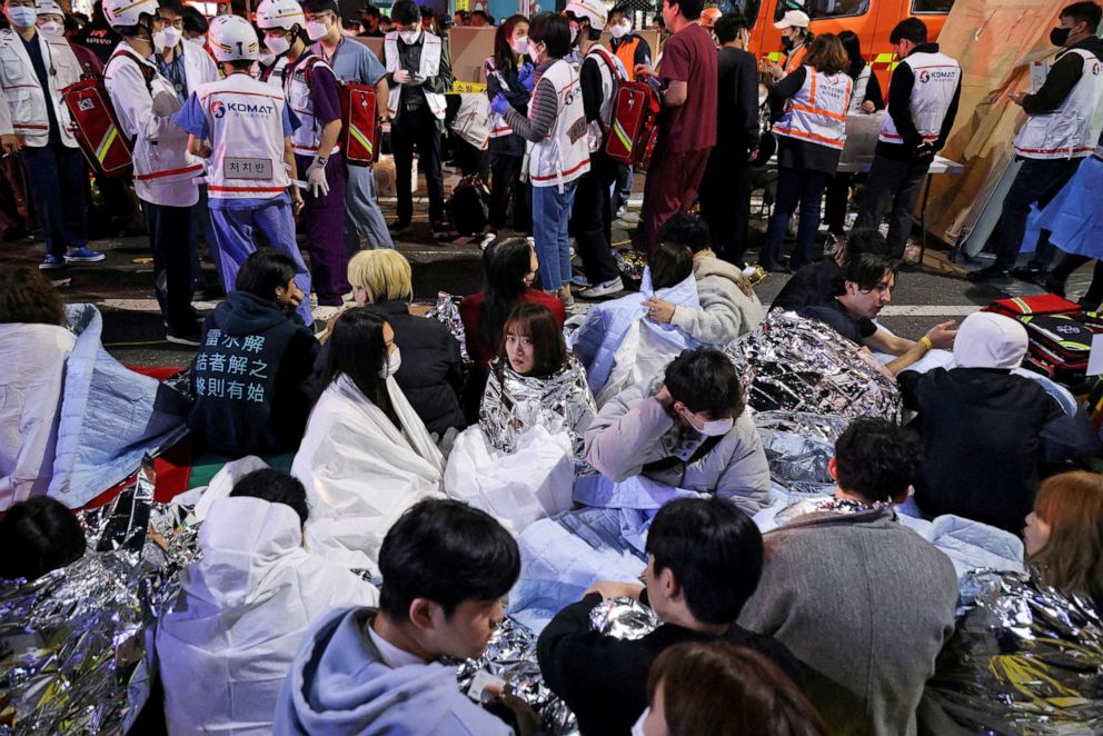 Foto: Personas sentadas en la calle después de ser rescatadas, en el lugar donde decenas de personas resultaron heridas en una estampida durante una celebración de Halloween en Seúl, Corea del Sur, el 30 de octubre de 2022.