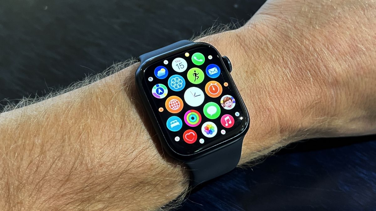 The Apple WAtch 8 on a blue desk and wrist