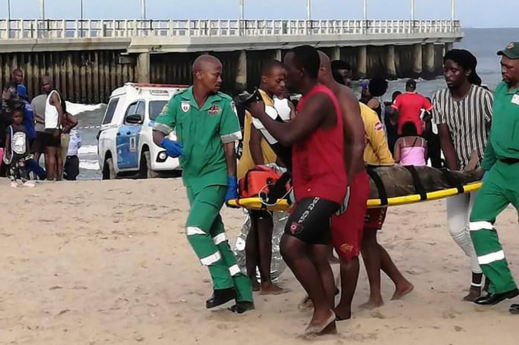 Los paramédicos llevan a una persona en una camilla en la playa de Bay of Plenty en Durban, Sudáfrica.