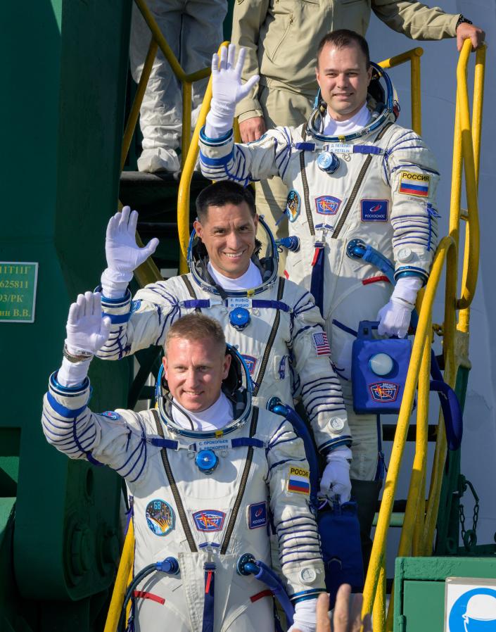 Dmitry Petlin de Roscosmos, arriba, Frank Rubio de la NASA, y Sergey Prokopyev de Roscosmos, abajo, saludan con la mano antes de abordar la nave espacial Soyuz MS22 para ir a la Estación Espacial Internacional el 21 de septiembre de 2023.