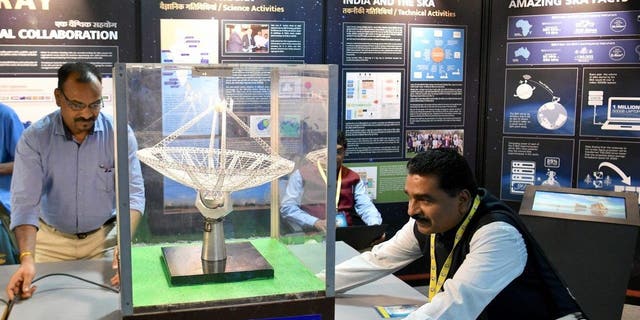 Un modelo organiza un modelo a escala de una antena de radiotelescopio gigante de ondas métricas (GMRT) en exhibición durante Vigyan Samagam, una exhibición científica masiva en múltiples lugares, en el Museo de Tecnología e Industria Visveswaraya en Bangalore el 29 de julio de 2019.