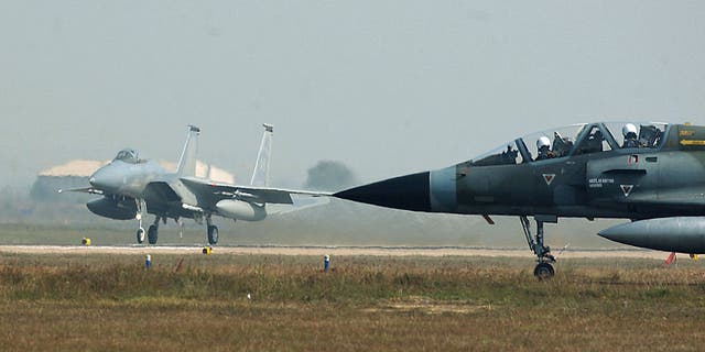En esta foto proporcionada por la Fuerza Aérea de los EE. UU., un Mirage de la Fuerza Aérea de la India espera para rodar hasta la pista (derecha) mientras un F-15C Eagle (izquierda) de la Fuerza Aérea de los EE. UU. despega el 13 de febrero de 2004 en la Estación de la Fuerza Aérea de Gwalior en India. . 