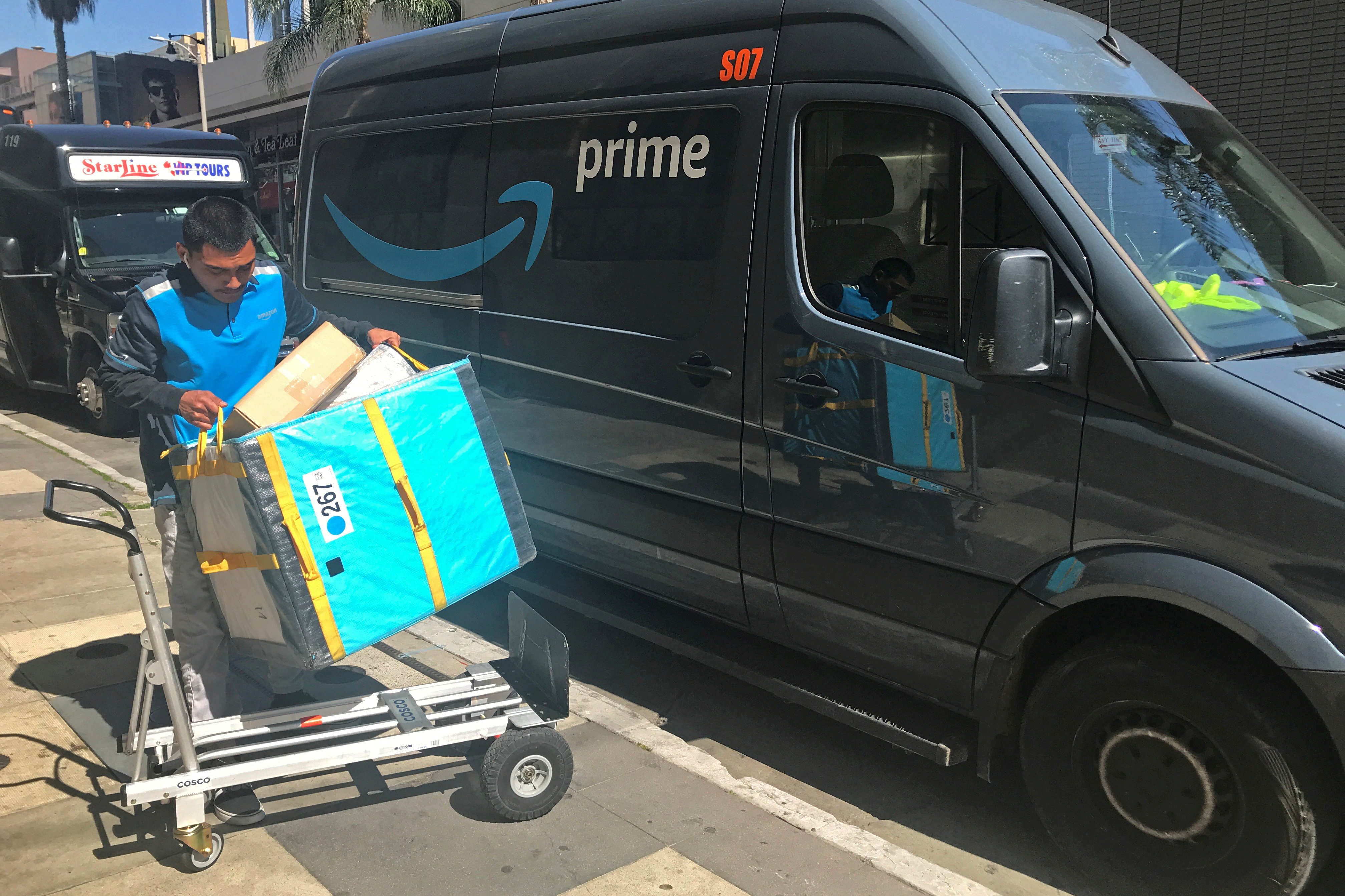 Un repartidor de Amazon carga un carrito desde una Prime Van en Los Ángeles