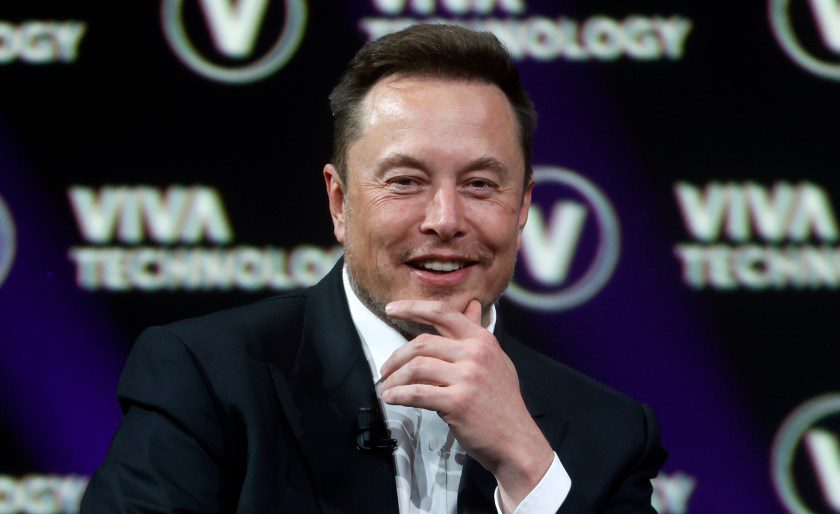 Imagen de Elon Musk con la mano en la barbilla y sonriendo levemente