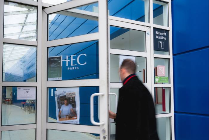 Un hombre atraviesa una puerta con un cartel de HEC Paris.