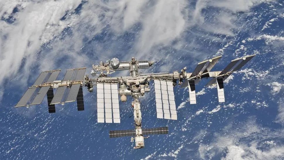 a space station floats above earth, over an ocean or sea