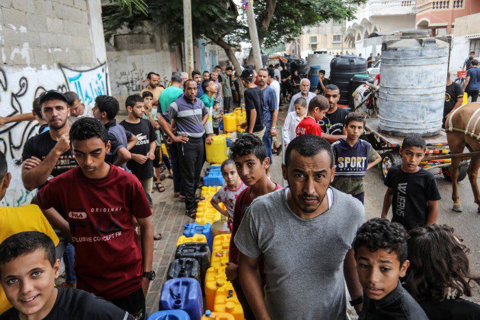 Palestinos esperan en un punto de agua para rellenar contenedores