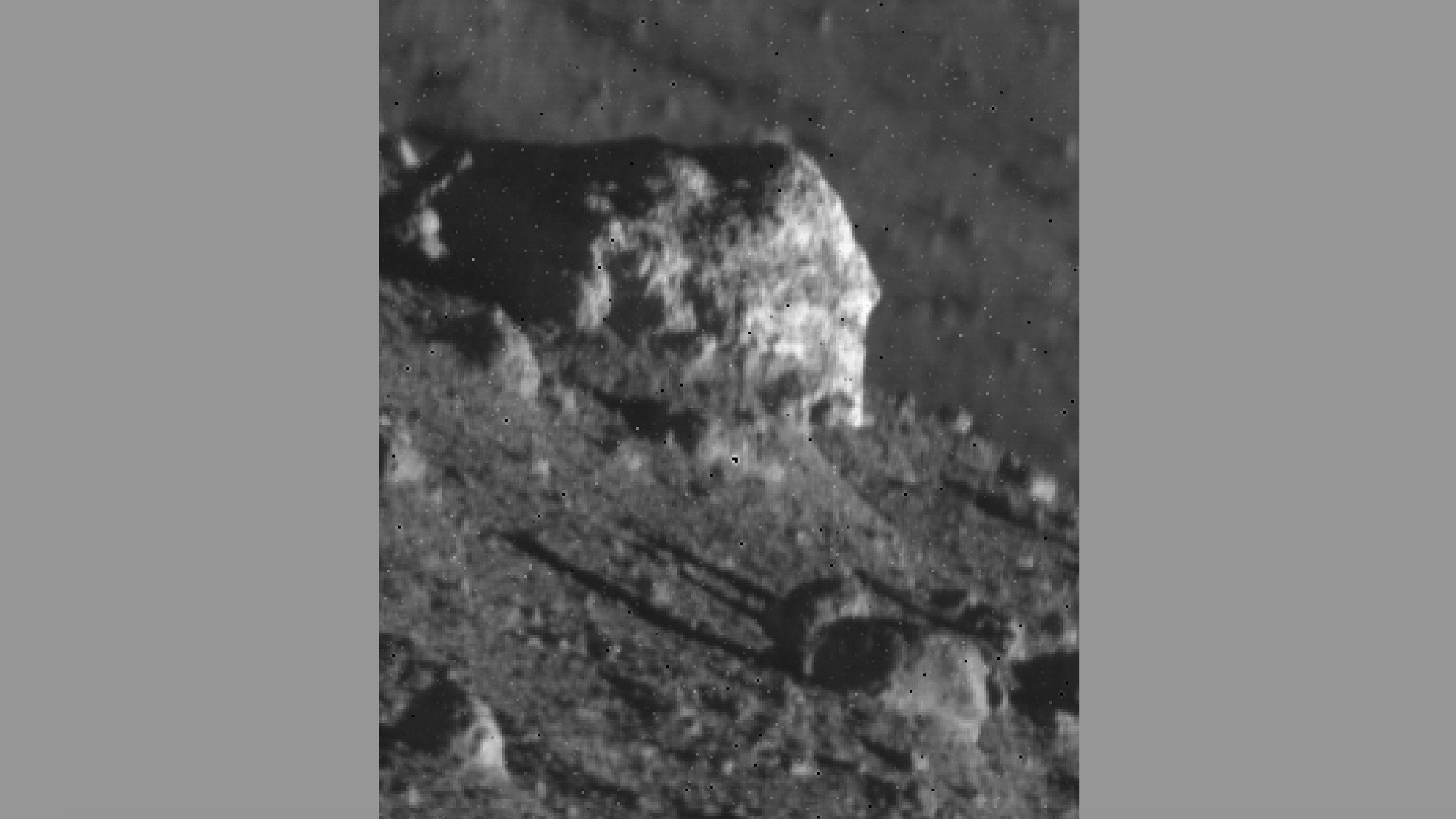 Una vista de cerca de una gran roca en la superficie de la luna, rodeada de rocas más pequeñas.