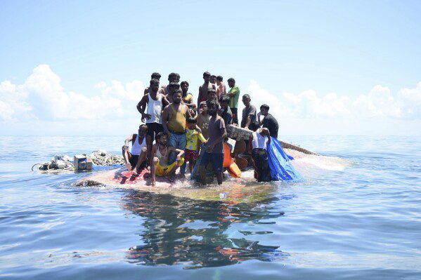 Refugiados rohingya se encuentran en su bote volcado antes de ser rescatados en las aguas frente a Aceh occidental, Indonesia, el jueves 21 de marzo de 2024. El bote de madera que transportaba a docenas de musulmanes rohingya volcó frente a la costa norte de Indonesia el miércoles, según pescadores locales.  (Foto AP/Reza Seif Allah)